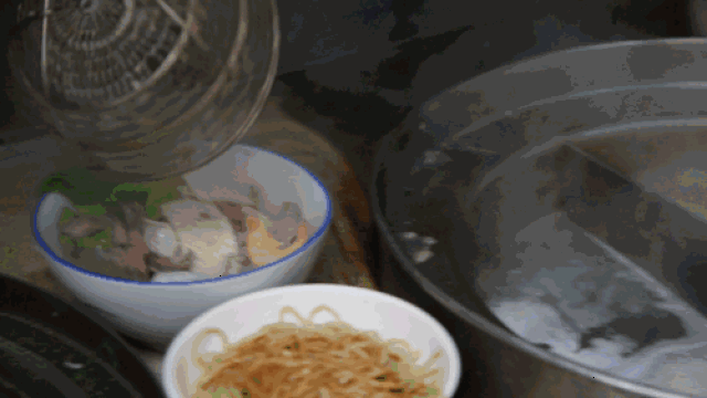 在漏勺中装满客人点的食材, 厨房小伙子手脚麻利的在锅里促了十几秒