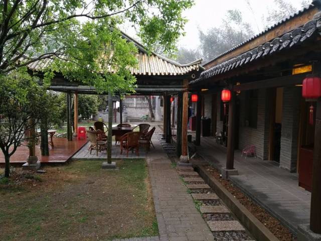 幢青砖石瓦的现代建筑和历史遗存的茅草土坯小屋,古朴民俗的农家小院