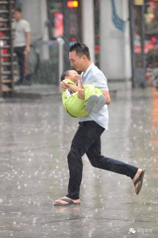 14日,佛山街头,一位男士抱着孩子在雨中狂奔.