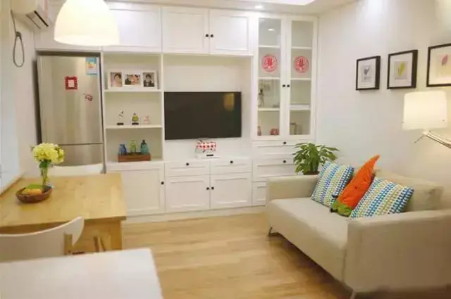 客厅电视背景墙打造了一排收纳柜,旁边设计了个嵌入式冰箱的位置,这样