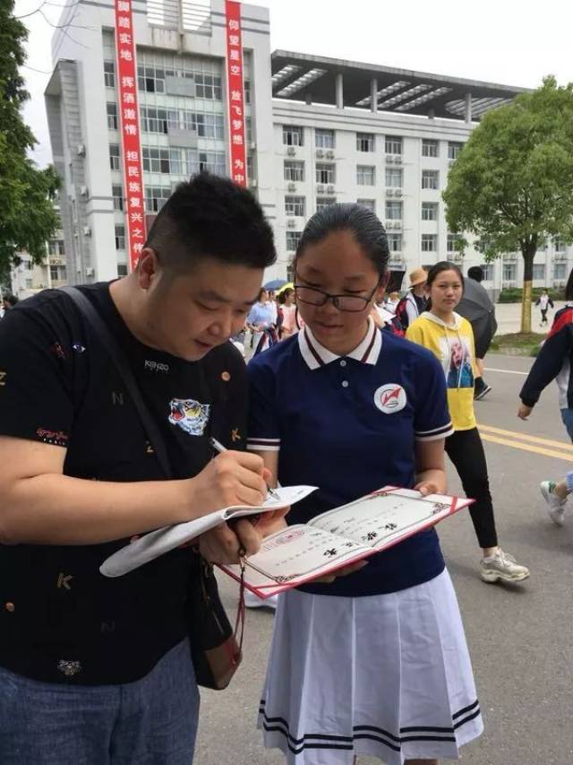 (沈嘉柯老师在广华中学校园内给获奖同学签名)