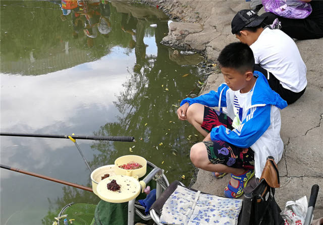 和家长一起来钓鱼的孩子们在湖边上玩耍.