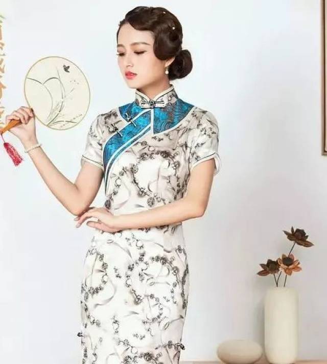 衣襟处有一条黛绿色的斜襟,为整袭旗袍增添了一抹色彩,显得生机勃勃
