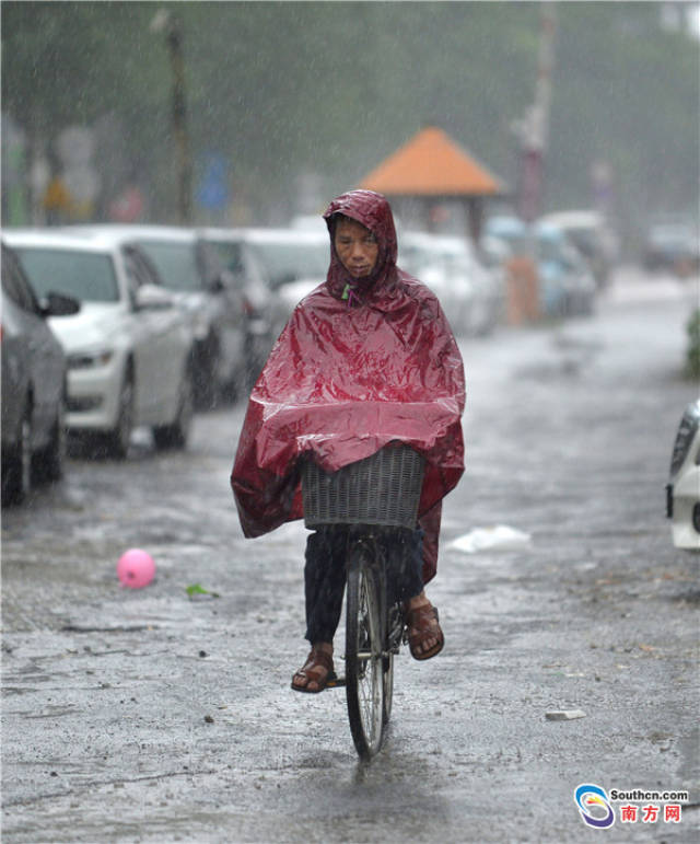 广州汇彩路,裹着雨衣的男子在雨中骑行.