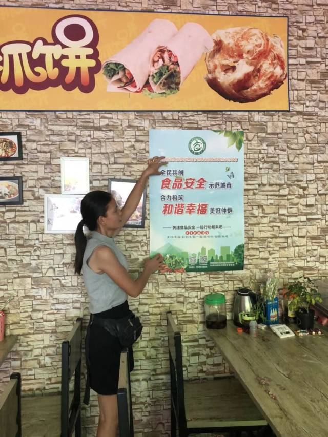 食品安全协管员在企业食堂和住宅小区外张贴创城宣传海报