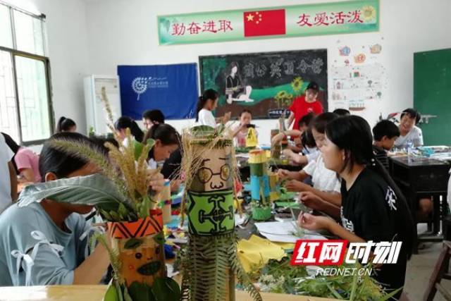 穿瑶族服饰的竹筒娃娃手工课上,志愿者指导当地学生制作竹筒娃娃,并