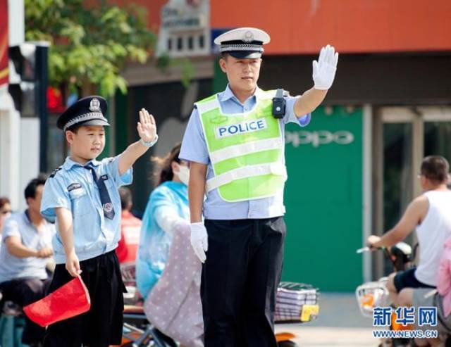 7月21日,"小交警"在民警的指导下体验指挥交通. 来源:北青网