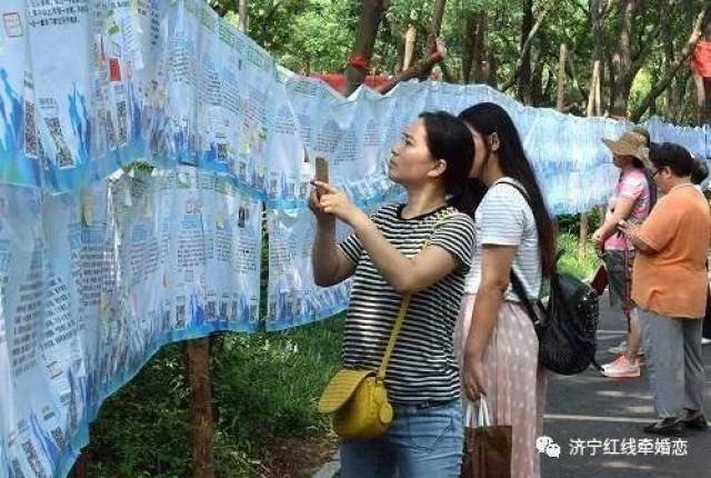 资料图:一名市民在济南千佛山公园举行的"七月七相亲大会"上用手机