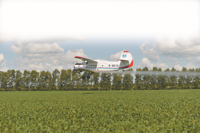 在黑龙江省九三垦区尖山农场,农用飞机正给大豆喷洒叶面肥和农药.