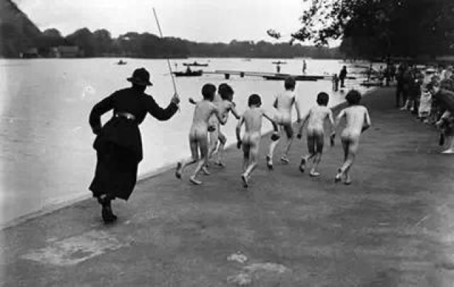 14,1926年几个赤身裸体的小孩在海德公园旁的湖里游泳,一名女警官正