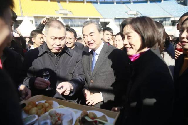 外交部部长王毅携夫人钱韦女士参观使馆摊位并品尝特色食物