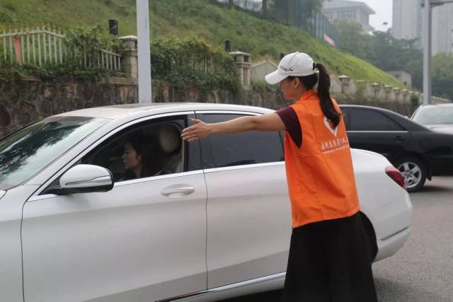 号护学岗志愿者协助指挥车辆倒车,及时提醒车尾周边安全情况
