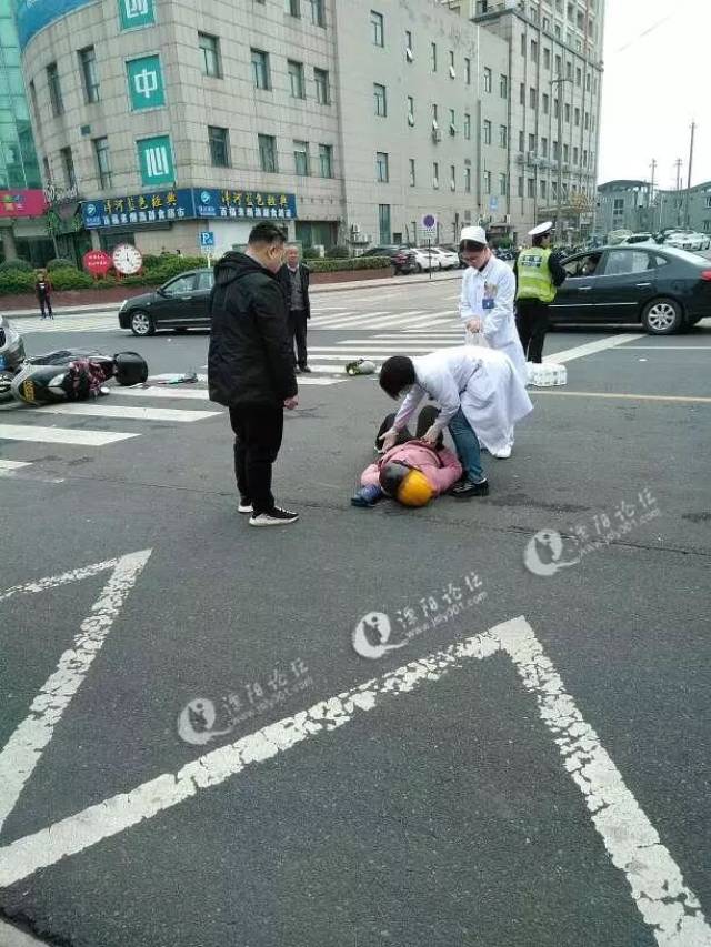 门口)的十字路口发生一起车祸,女的躺在地上,摩托车上物品洒了一地,不