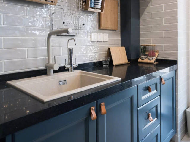 使用了浅灰色的墙,橱柜的台面使用了黑色的石材,搭配着深蓝色的柜门