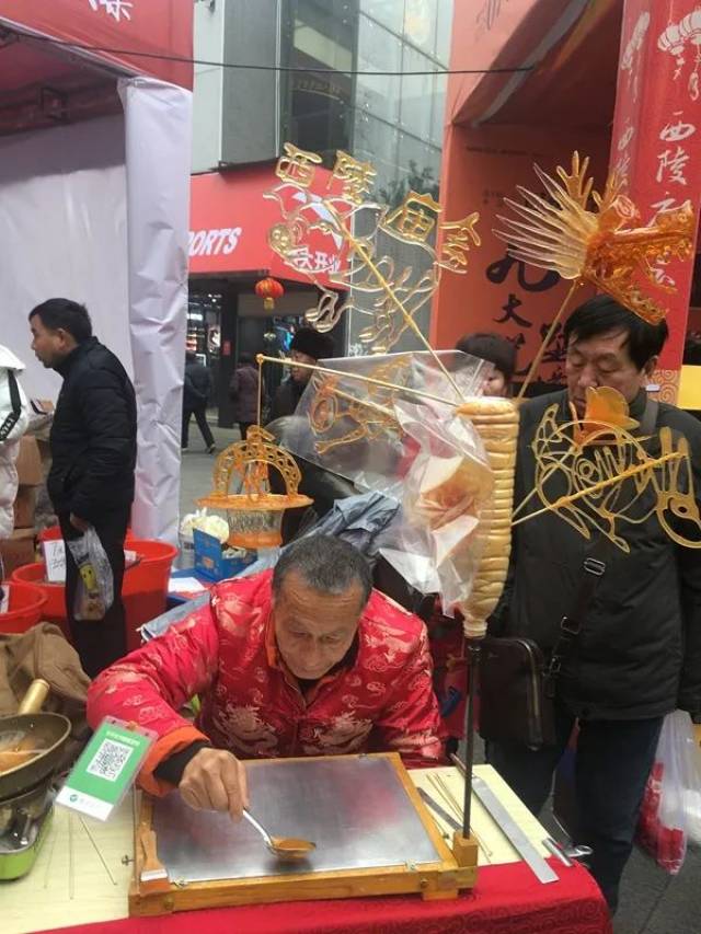 路边卖糖人的摊位上,用麦芽糖制作的大大的"西陵庙会"四个字吸引了