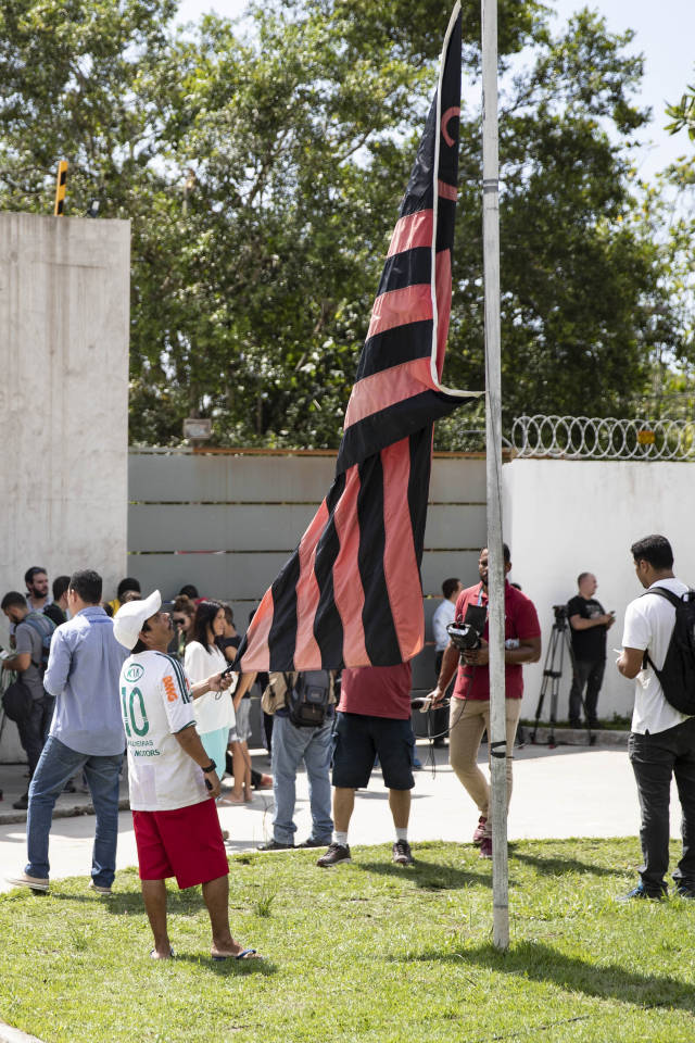 弗拉门戈俱乐部足球训练基地外,一名当地居民手握弗拉门戈俱乐部旗帜