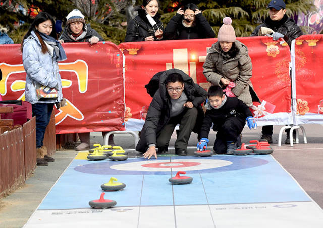 2019年2月10日,雕塑公园迎冬奥新春体育庙会上,市民在体验冰壶运动.