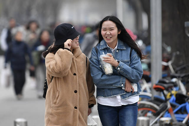行人在大风天气里出行.行人纷纷穿上厚衣服出行.