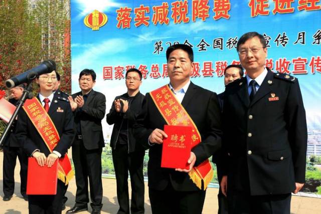 图为无极县税务局局长王彦军向吕保民发放聘书.