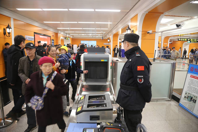 地铁1号线新疆大街站的安检人员正在仔细检查乘客的背包,维护乘车安全