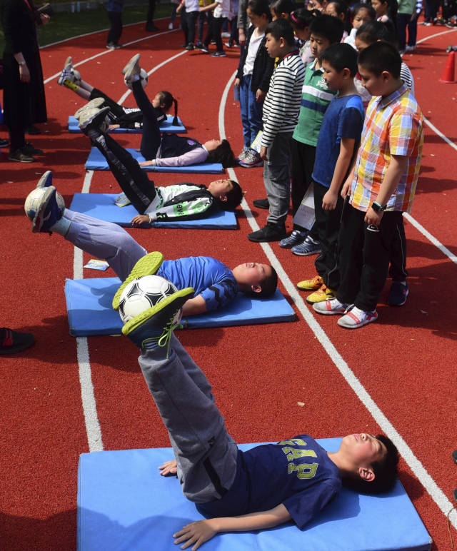 学生在校园足球嘉年华活动上进行夹球仰卧举腿比赛.