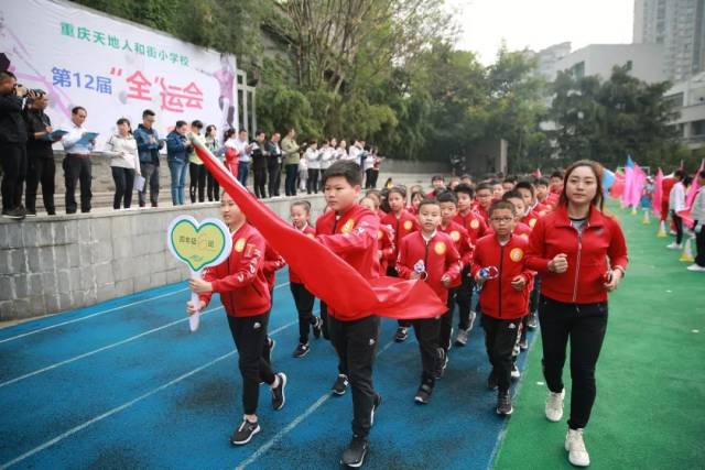 天地人和街小学,孩子们身着五彩缤纷的班服,挥舞着绘有不同花纹的班旗