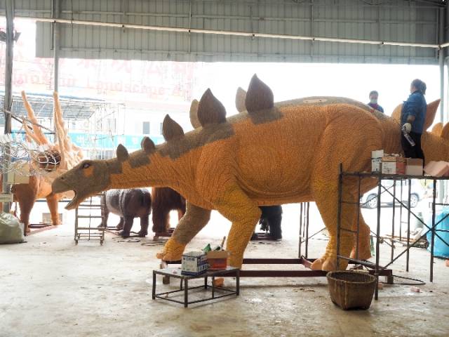 车间内工人正在给仿真恐龙的巨大爪子层层涂抹颜料,让它看起来更真实.