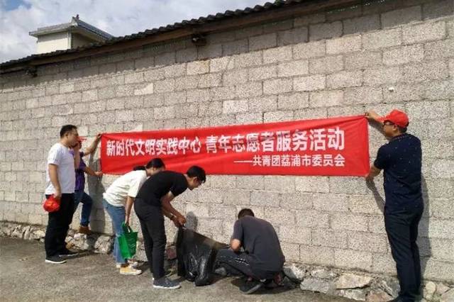 团市委青年志愿者沿途张贴宣传横幅 志愿者们发放宣传资料,向村民