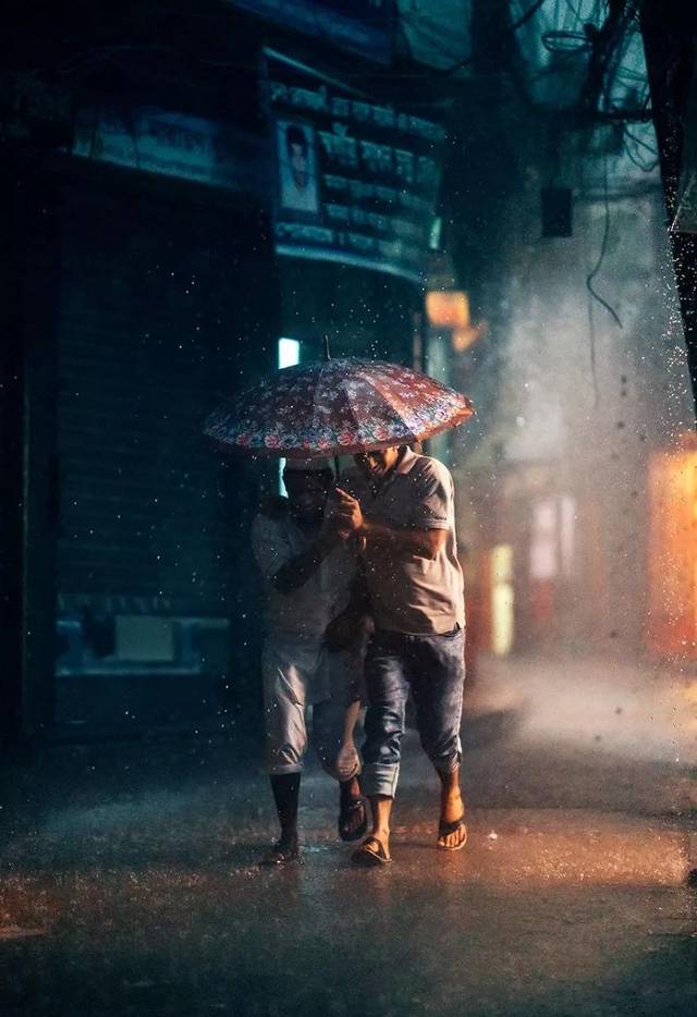 一对好朋友共同撑着一把伞走在街道上.