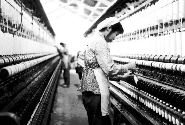 贵驷纺织厂车间,纺织工人检查机器生产情况