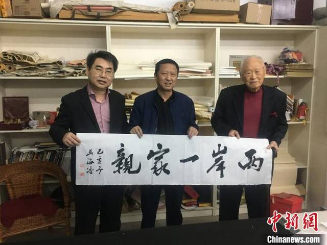 图为斯孝坤(最右)赠家乡"两岸一家亲"书法作品.