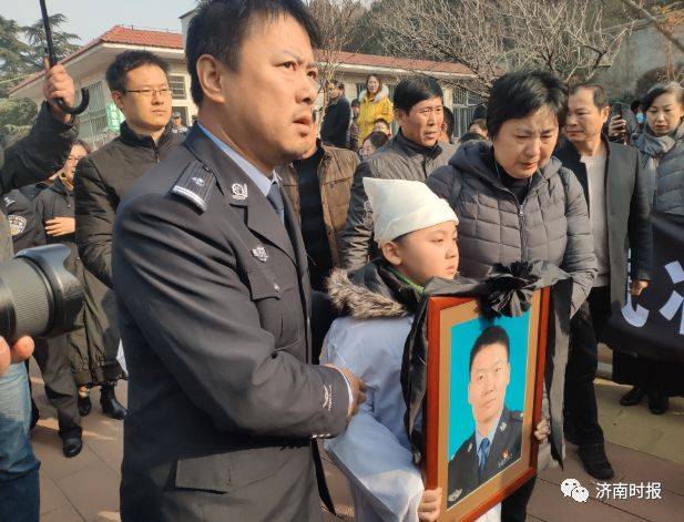 张勇的儿子抱着父亲的遗像缓缓走入骨灰堂.