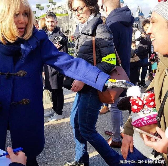 66岁法国总统夫人布丽吉特参加迪士尼活动,lv斗篷外套减龄,半素颜也