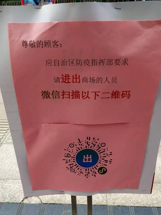上面写着"请佩戴口罩, 出入商场请扫二维码", 旁边还有工作人员引导