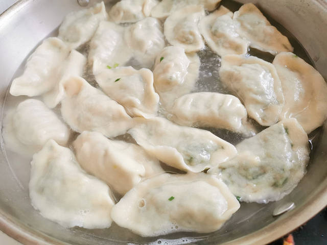 锅中倒入半锅水烧开,把饺子一个个下入锅中,煮开后再加入一些凉水