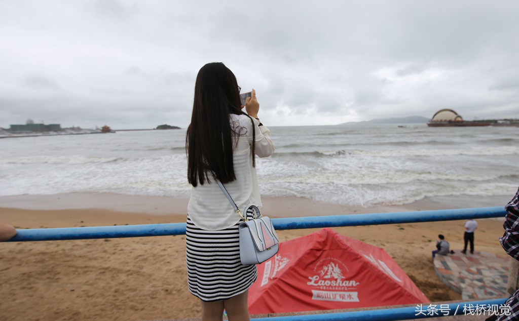 2017年10月1日,一位美女在青岛栈桥海水浴场岸边观赏大浪.