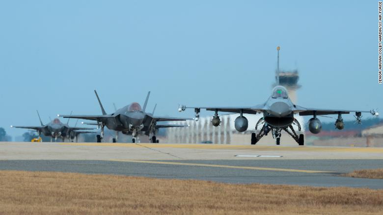 韩国群山空军基地跑道尽头正准备起飞的一架f-16和4架f-35a