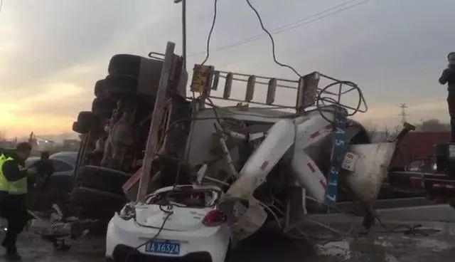 从画面中可以看到,一辆水泥罐车侧翻在了一辆白色轿车上