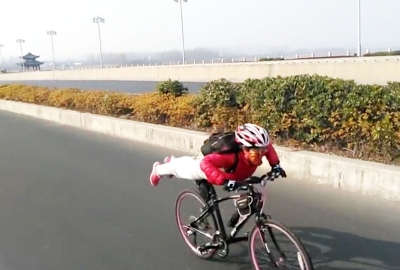 一名骑手骑着单车行驶在广陵大桥上,在下坡时其突然趴在单车上,身体与