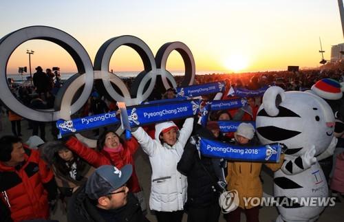 資料圖片:1月1日,在江陵鏡浦海邊,平昌冬奧會志願者們在宣傳冬奧.