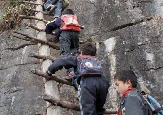 上学路上,一位小学教师背着年幼点的学生,年龄大点的则手牵着手