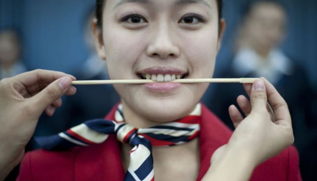 针锋相对动车乘务员礼仪培训女孩们咬住筷子练习微笑