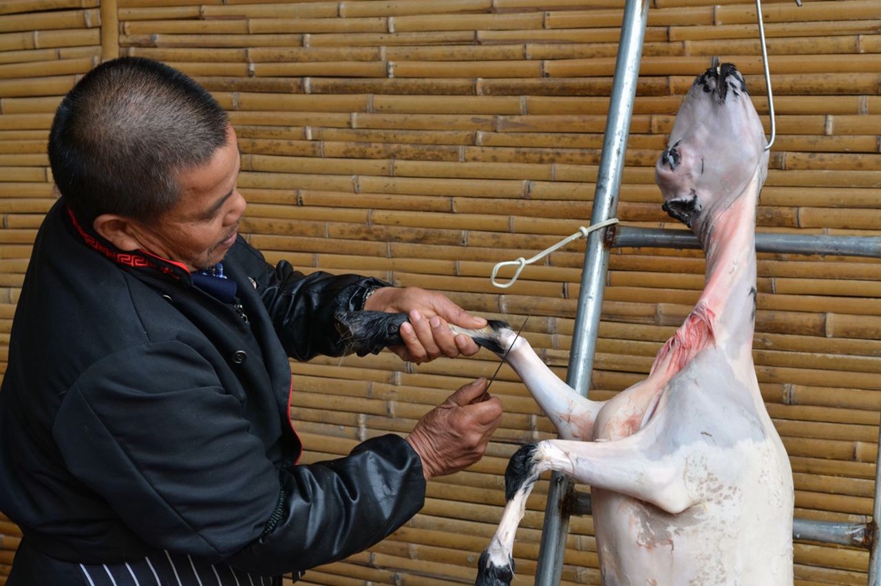 然後再從羊腹內進刀把羊脊骨砍破(但脊背肉要相連),掏出內臟後洗淨