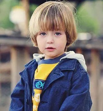 可爱帅气的圆脸小男孩有着一头乌黑丰盈的直发,剪裁成超短毛寸短发