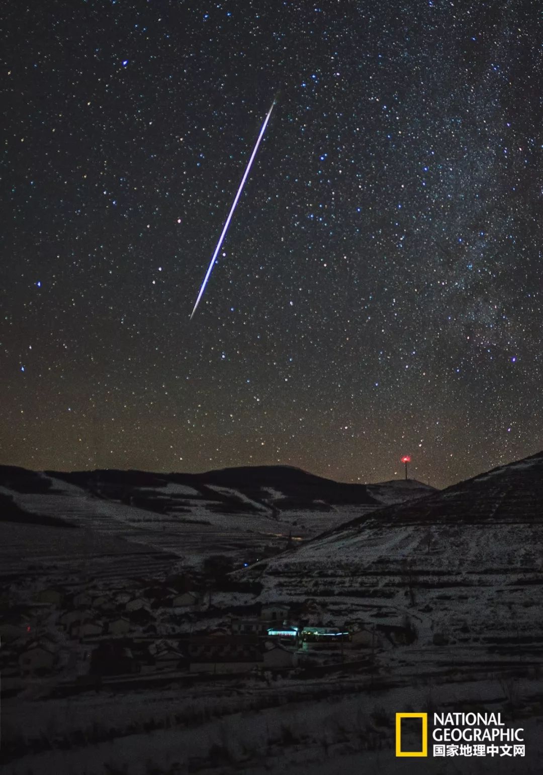 双子座流星雨前夜,一颗明亮的火流星划过天路边的村庄上空