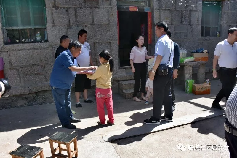 栗东生同志向贫困户的子女赠送学习用品,并鼓励她们好好学习