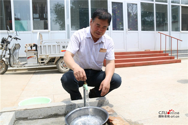 灌河村村民赵志轩正在接自来水管的长江水.