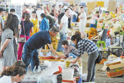 6月15日,在新疆九鼎农产品批发交易市场,市民在挑选瓜果.