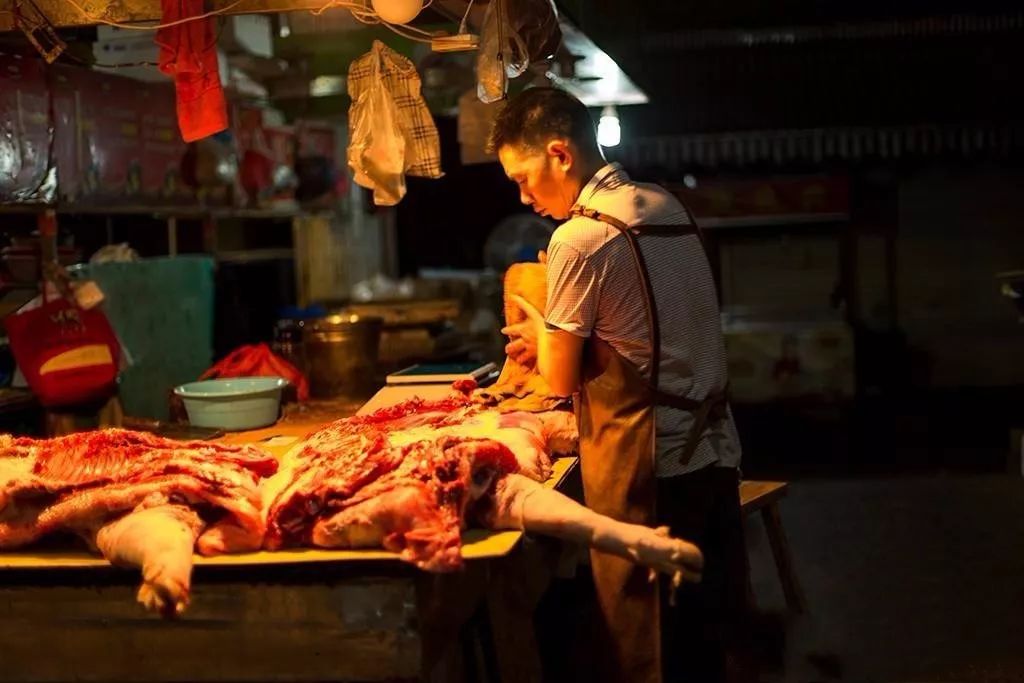 肉攤子上,攤主正在加緊整理半扇豬.開市前他會根據不同部位分解豬肉.