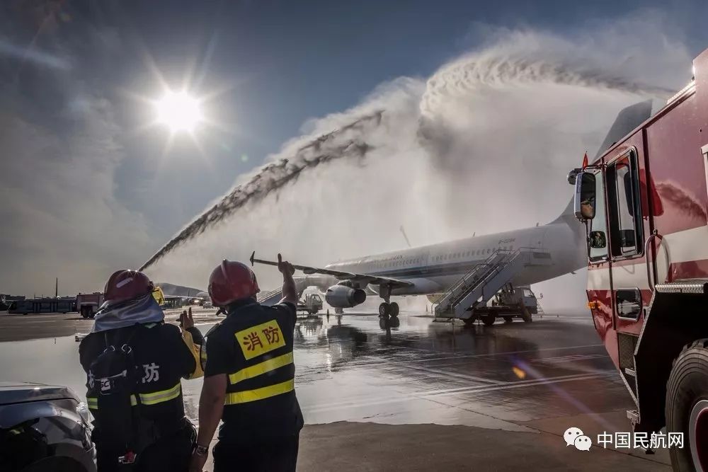 紧急备降的航空器冒着浓烟,大连机场消防车对航空器进行喷水灭火,一名